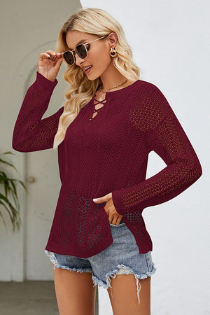 Burgundy openwork knit tunic with lace-up neckline and long sleeves.