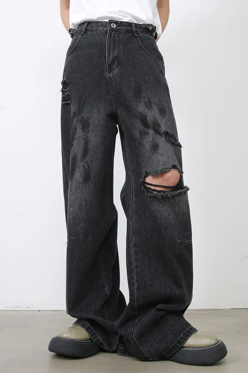 Rugged relaxed fit dark wash denim jeans with distressed rips and wide leg.