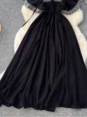 Black embroidered V-neck maxi dress with a tie waist and flowing skirt.