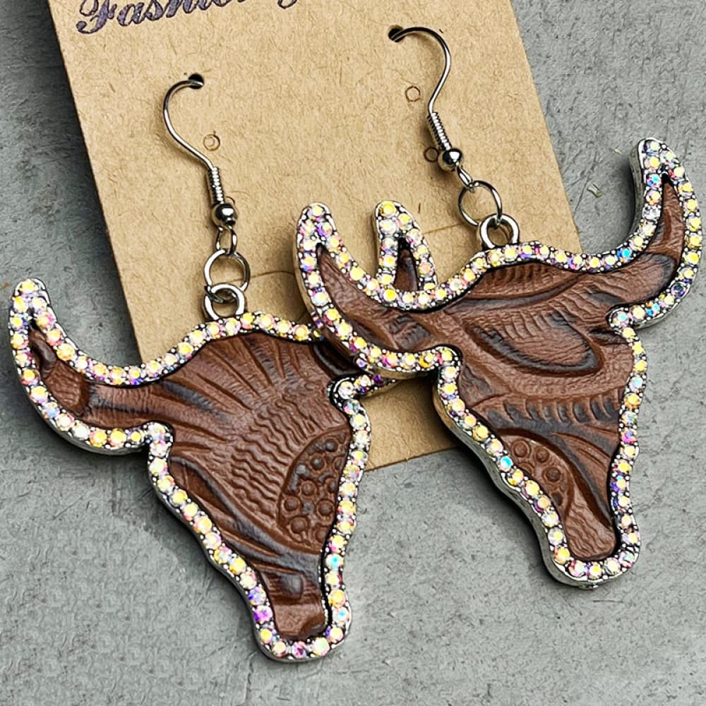 Crystal-trimmed bull skull earrings in dark brown with embossed detail and silver hooks.