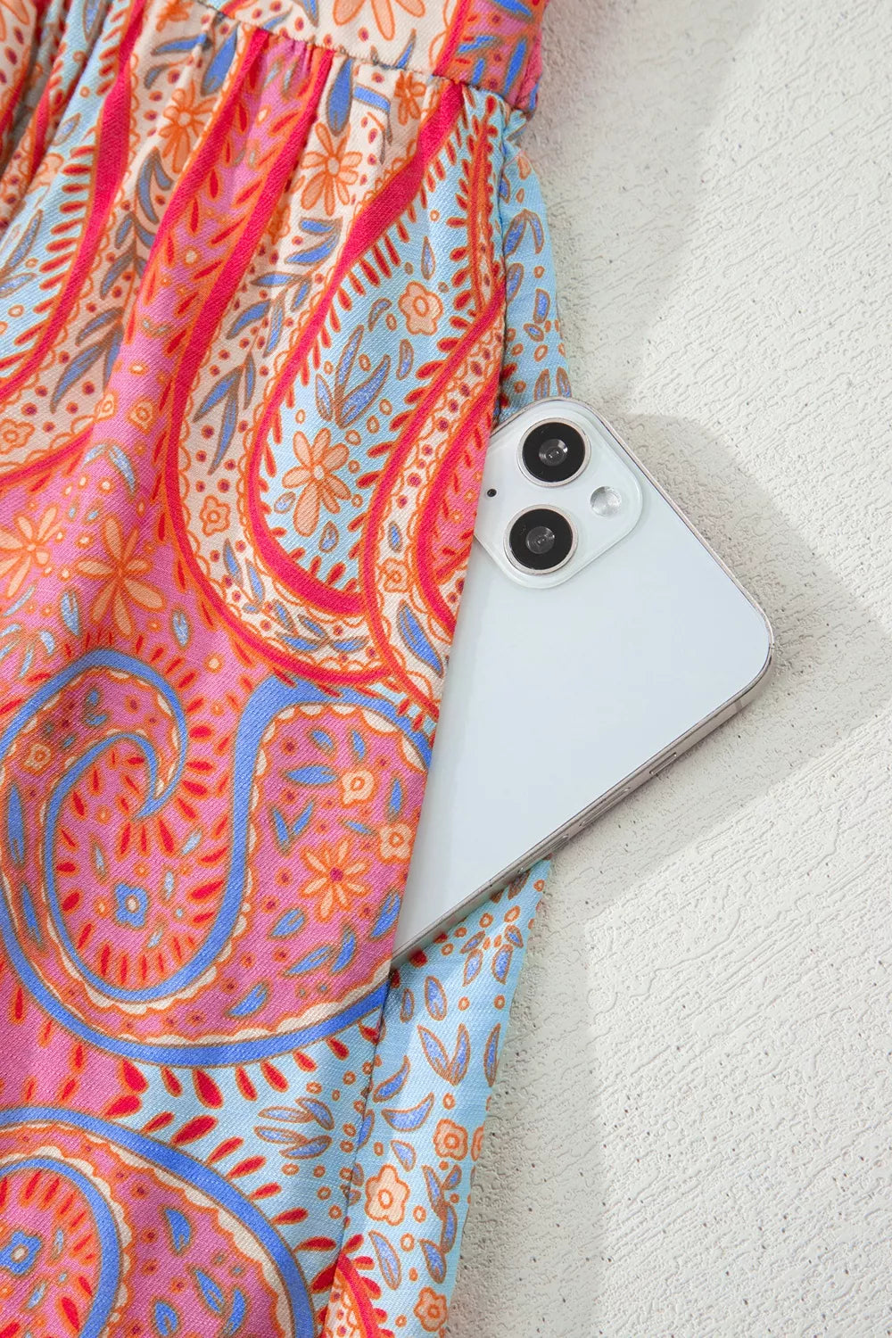 Paisley print boho dress with a phone in the pocket, featuring coral and blue floral patterns.