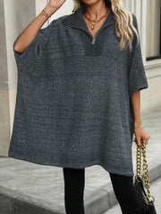 Dark gray knit asymmetrical zip-neck poncho with short sleeves and a collar.
