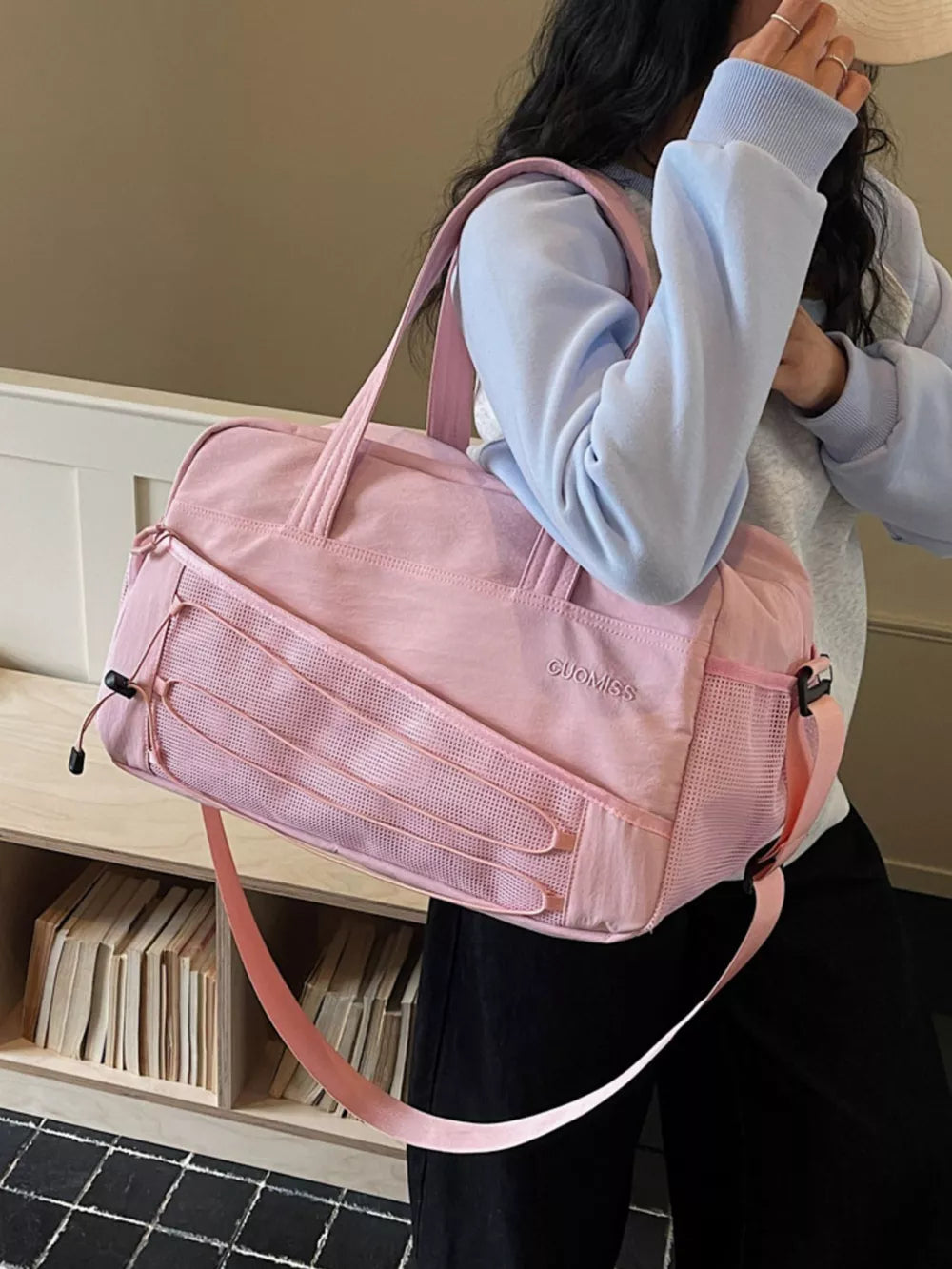 Pink nylon travel bag with bungee cord detail and adjustable strap.