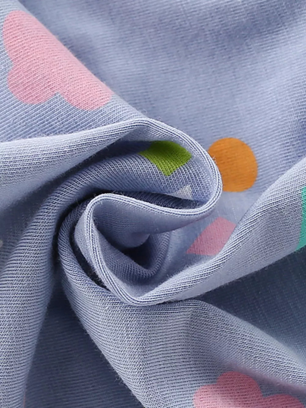 Baby dress with abstract print in pink, green, and orange on blue cotton blend fabric.
