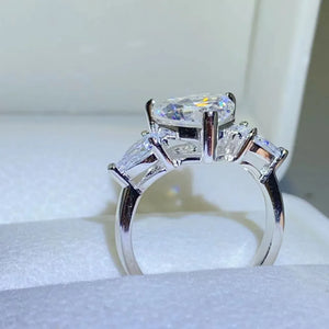 Silver ring with a large heart-cut diamond and two pear-cut side stones.
