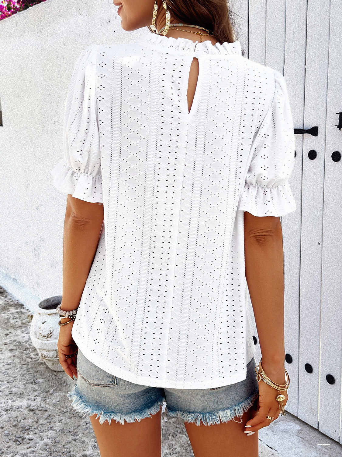 White eyelet blouse with ruffled mock neck and puff sleeves.