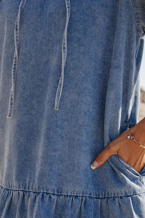 Denim mini dress in medium wash with ruffle hem and drawstring neckline.