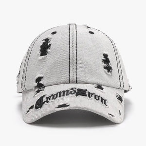 Distressed baseball cap in light gray denim with black embroidered text and rips.