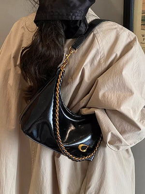Black patent crescent shoulder bag with gold chain strap and hardware