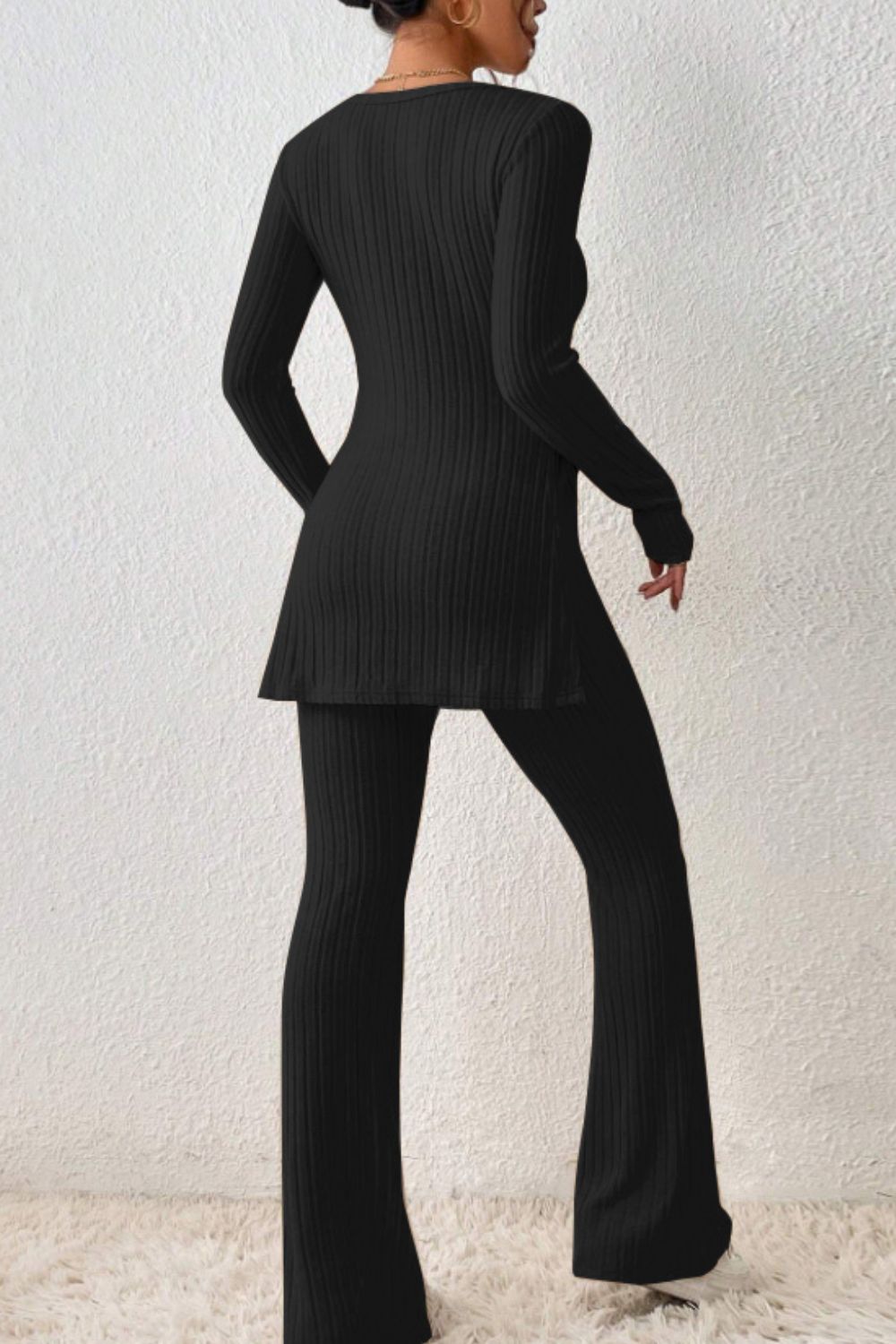 Black ribbed knit co-ord set with flared pants and side slit tunic.