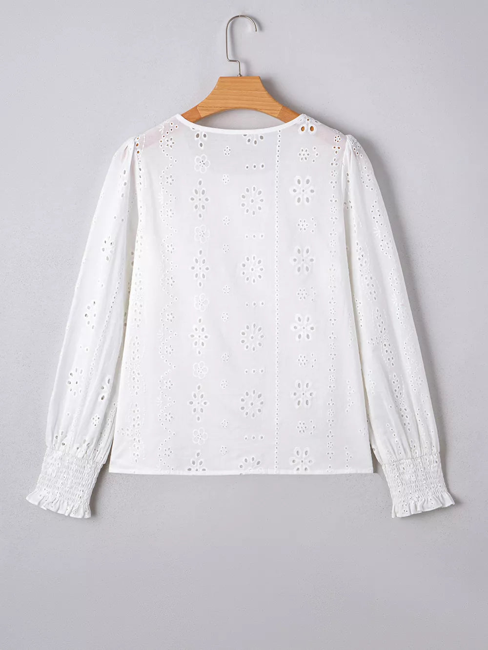 White cotton blouse with eyelet embroidery, ruffled cuffs, and smocked wrists.