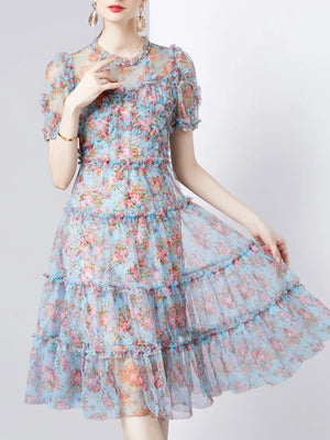 Ruffled floral dress with short sleeves and tiered skirt in light blue with pink and coral flowers.
