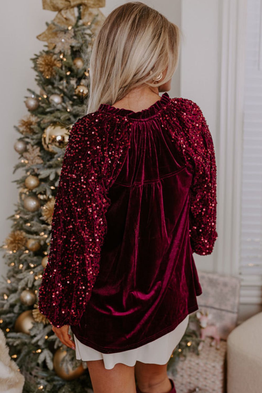 Red velvet blouse with sequin sleeves and ruffled neckline.