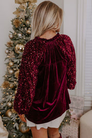 Red velvet blouse with sequin sleeves and ruffled neckline.