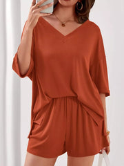 Orange-red V-neck two-piece lounge set with cuffed sleeves and drawstring shorts.