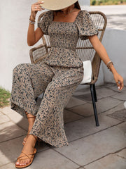 Taupe floral smocked bodice jumpsuit with puff sleeves and wide-leg palazzo pants.