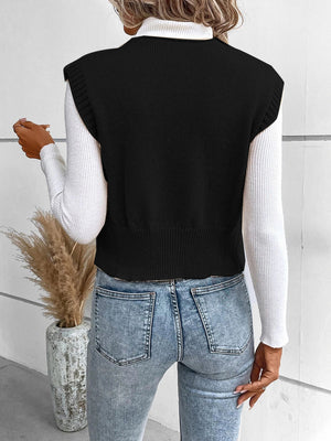 Black knit vest with ribbed trim and crew neck, worn over a white turtleneck.