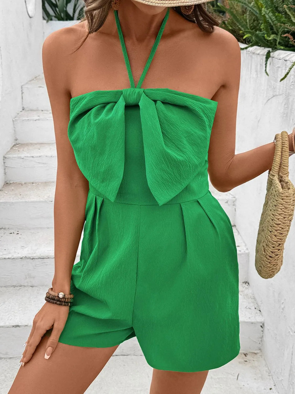 Green halterneck romper with bow-front detail and smocked back.