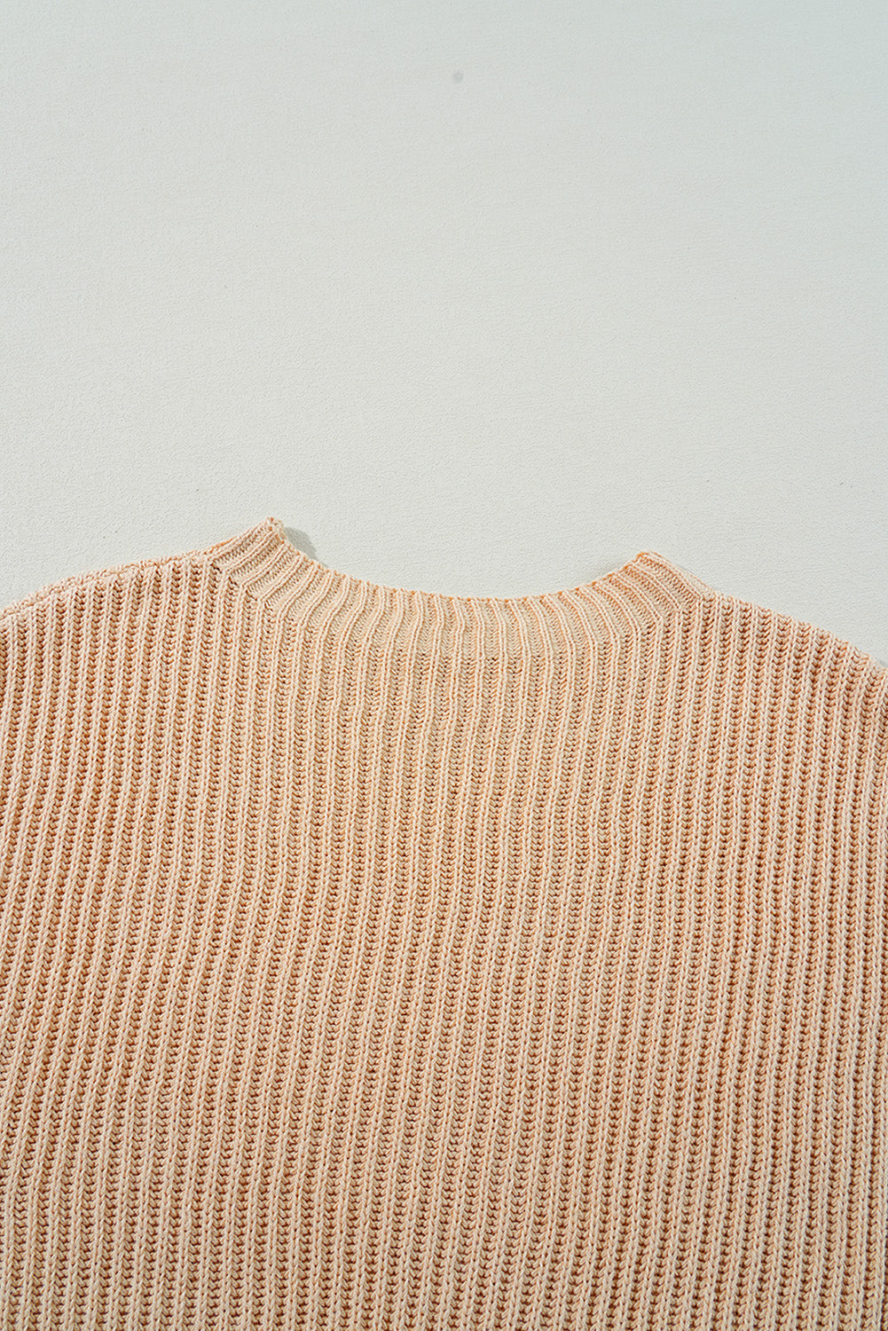 Tan ribbed knit pullover sweater with asymmetric hem detail.
