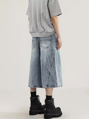 Men's light wash denim capris with a relaxed fit and wide leg, showing back pockets and distressed details.