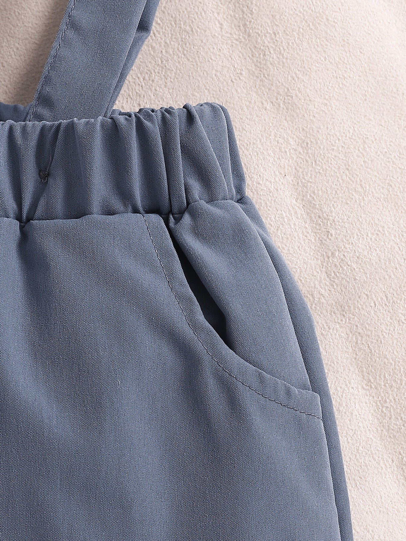 Sky blue baby suspender shorts with elastic waistband and pocket detail.