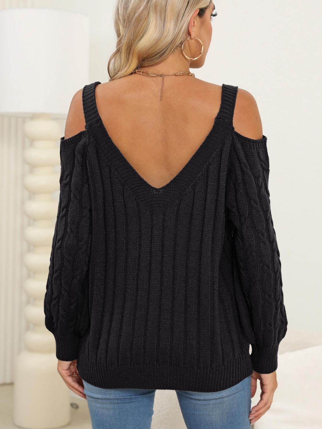 Black open shoulder cable knit sweater with V-neck and ribbed detail.