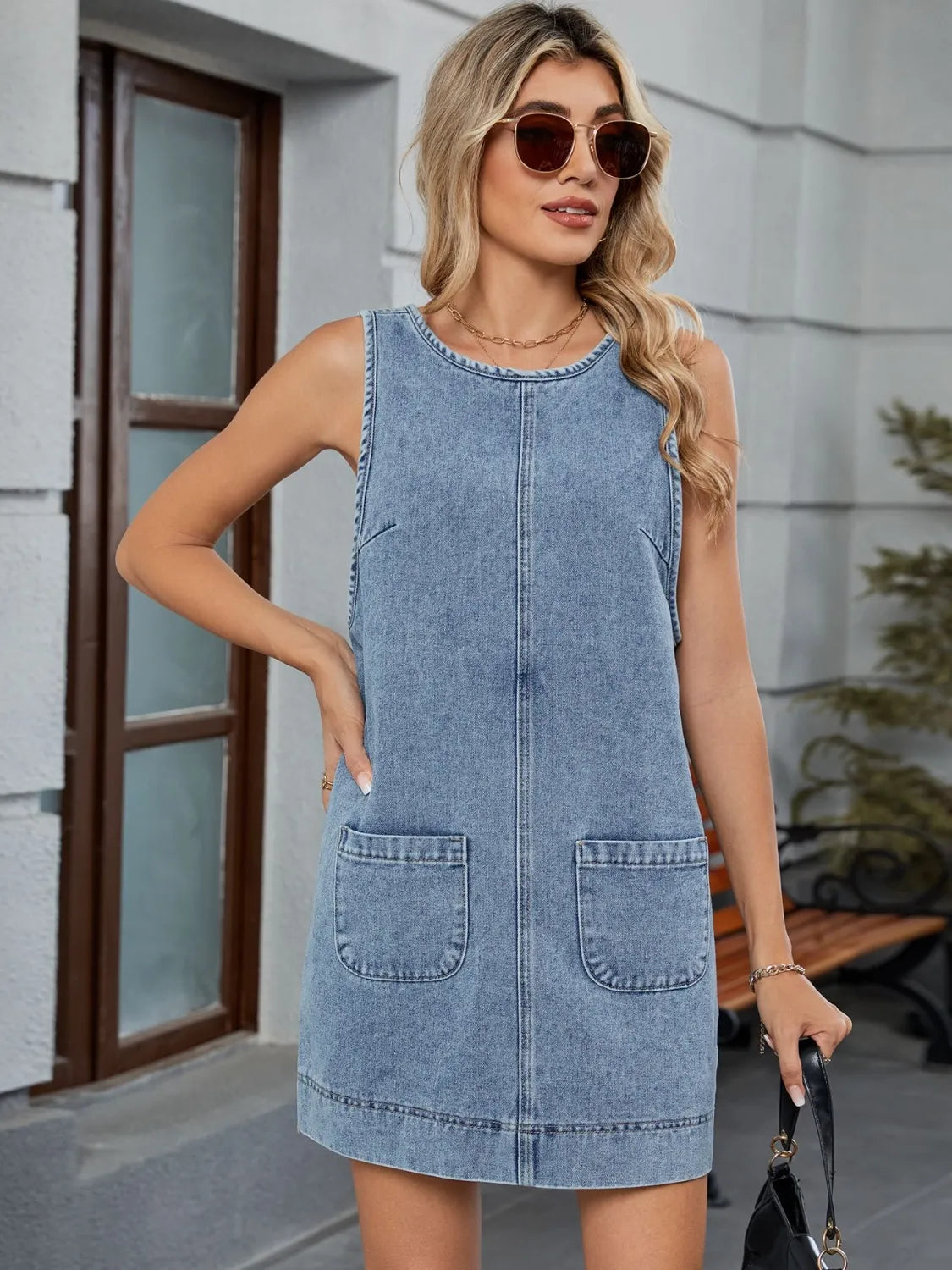 Light blue denim sleeveless pinafore dress with patch pockets and back detail.