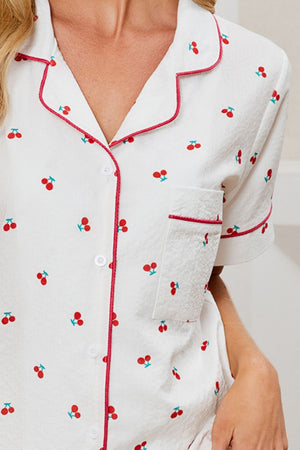 White pajama set with cherry print, red piping, and textured fabric.