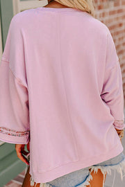 Dusty pink sweatshirt with floral peace sign embellishment on sleeves.