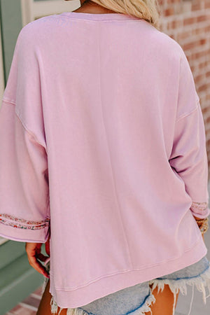 Dusty pink sweatshirt with floral peace sign embellishment on sleeves.