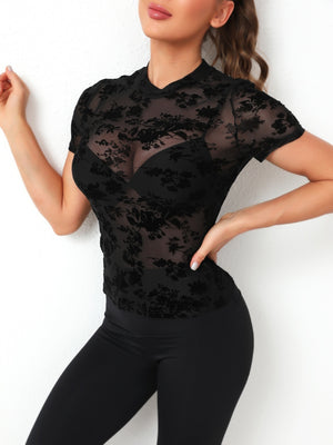 Black velvet floral mesh mock neck top with short sleeves, styled with a bra.