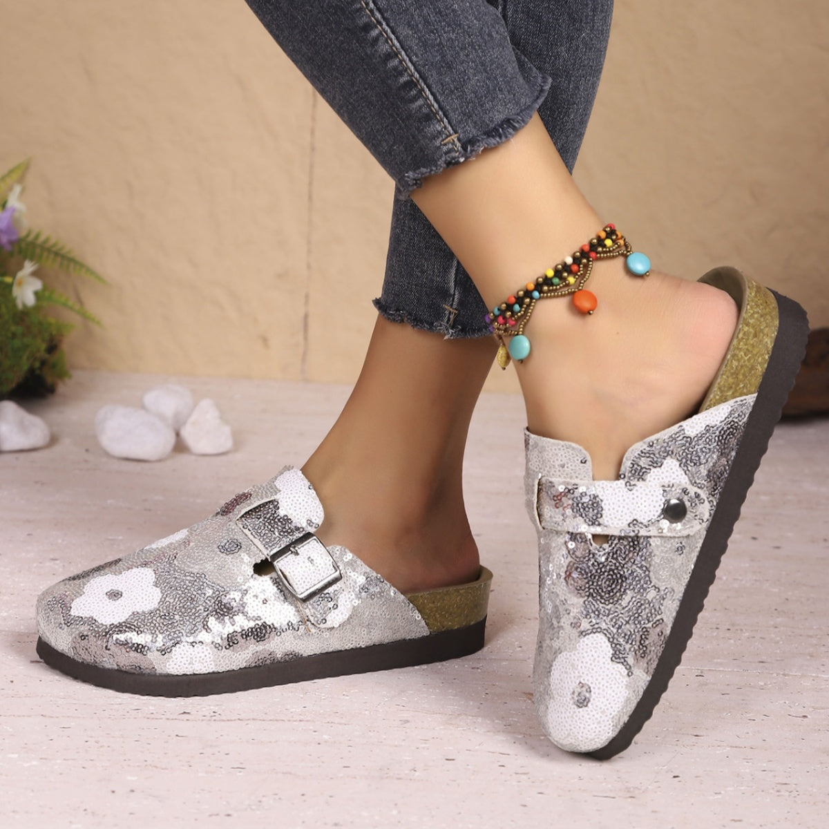 Sparkling sequin slip-on mules in white with floral pattern and decorative buckle.