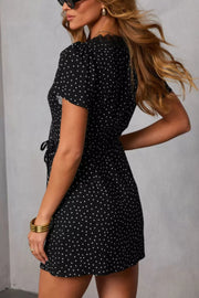 Black polka dot wrap mini dress with lace trim and short sleeves.