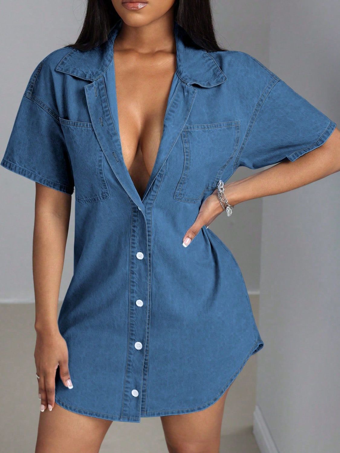 Oversized denim shirt dress in medium wash with a deep plunge neckline, collared, short sleeves, and button front.