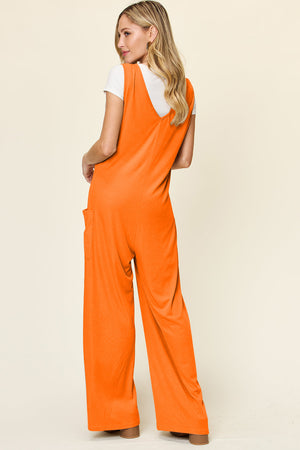 Tangerine wide-leg pocket jumpsuit with deep V-neck and side pockets, styled with a white tee.