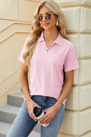 Blush pink textured polo shirt with V-neck and short sleeves, featuring a pocket detail.