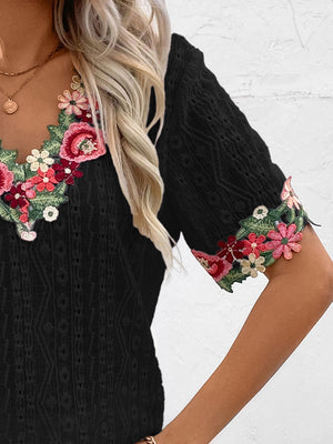 Black eyelet peasant blouse with embroidered floral V-neck and sleeve details.