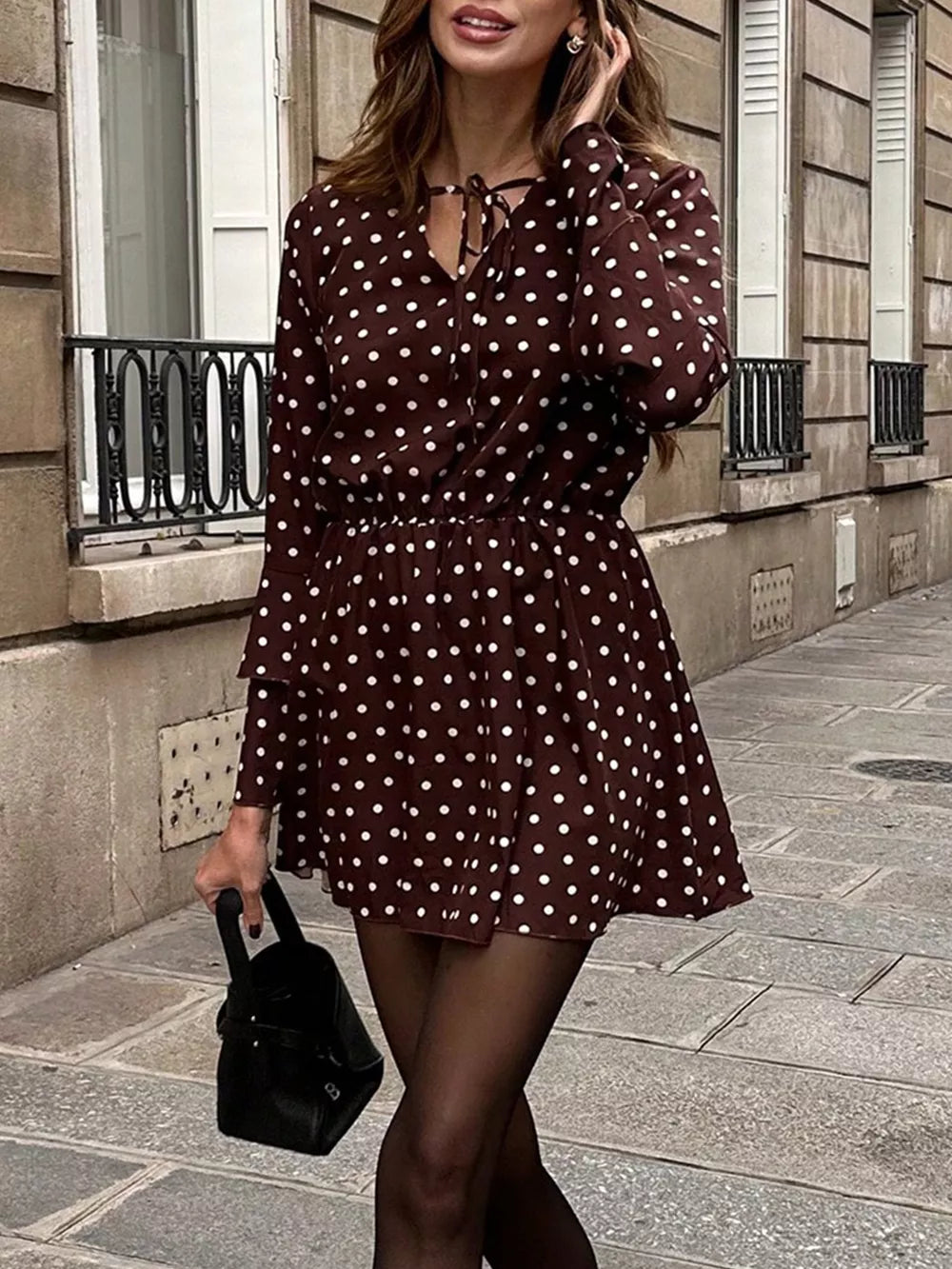 Brown polka dot mini dress with V-neck and tie detail, long sleeves, elastic waist