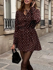 Brown polka dot mini dress with V-neck and tie detail, long sleeves, elastic waist