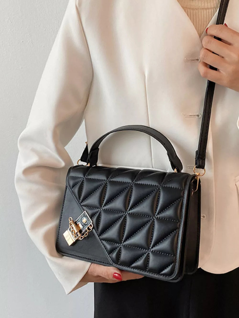 Black diamond quilted PU leather crossbody bag with gold lock detail.