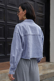 Light wash denim cropped trucker jacket with raw hem and button cuffs.