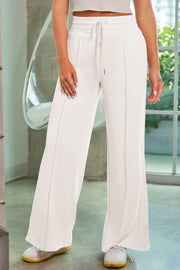 White palazzo joggers with drawstring waist and center seam detail.