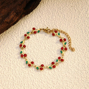 Gold-plated bracelet with red cherry clusters and green leaves, adjustable chain.