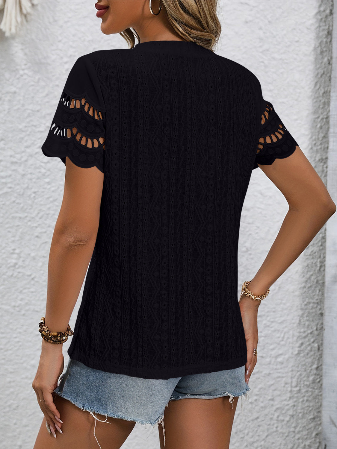 Black eyelet blouse with scalloped short sleeves and a textured pattern.