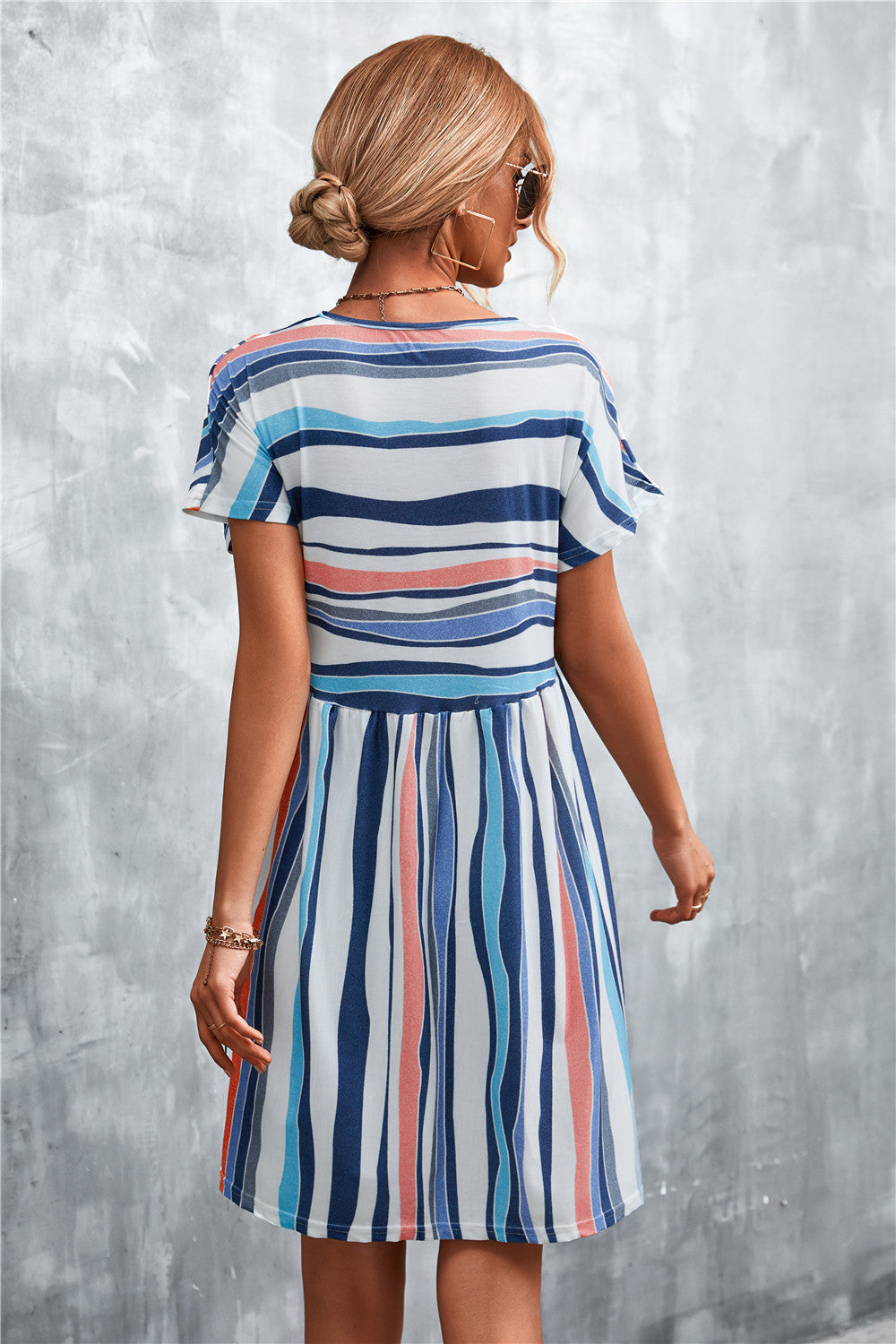 Striped yoke-seam trapeze dress with short sleeves and a flared skirt in multi-color stripes.