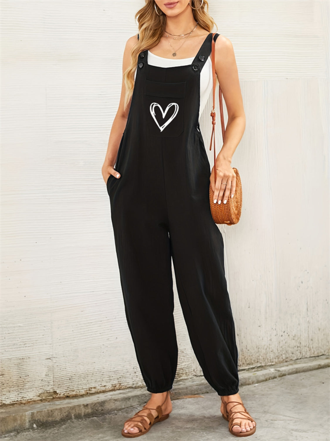 Black cotton overalls jumpsuit with heart pocket detail and button straps.
