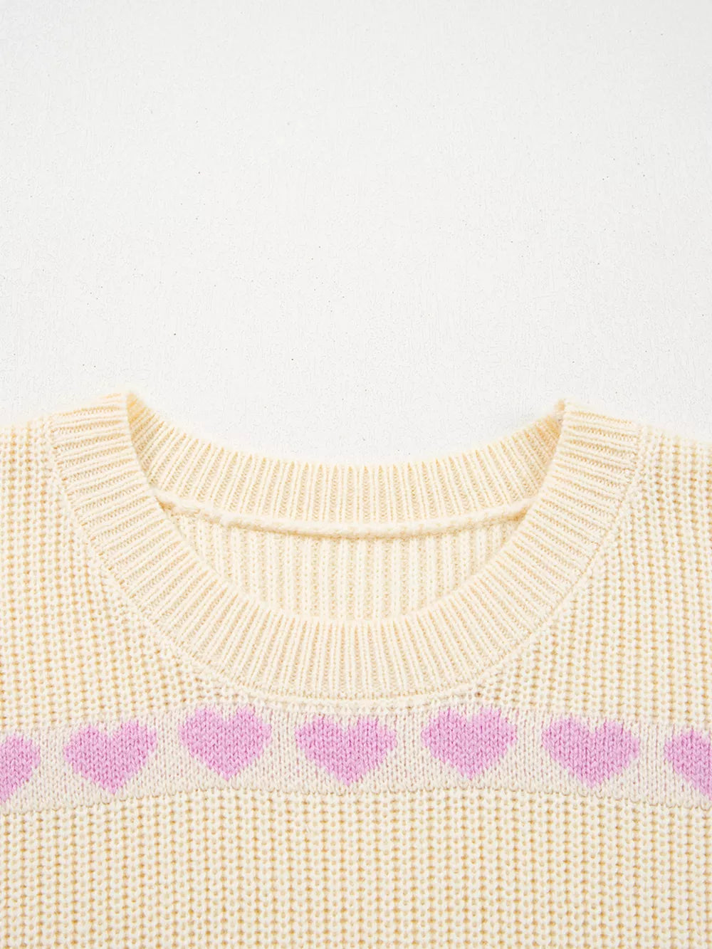 Cream knit sweater with a pink heart pattern and crew neck.