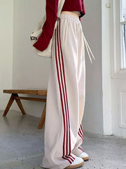 Cream maternity joggers with red side stripes and drawstring waist.