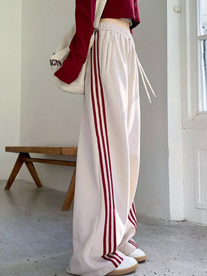 Cream maternity joggers with red side stripes and drawstring waist.