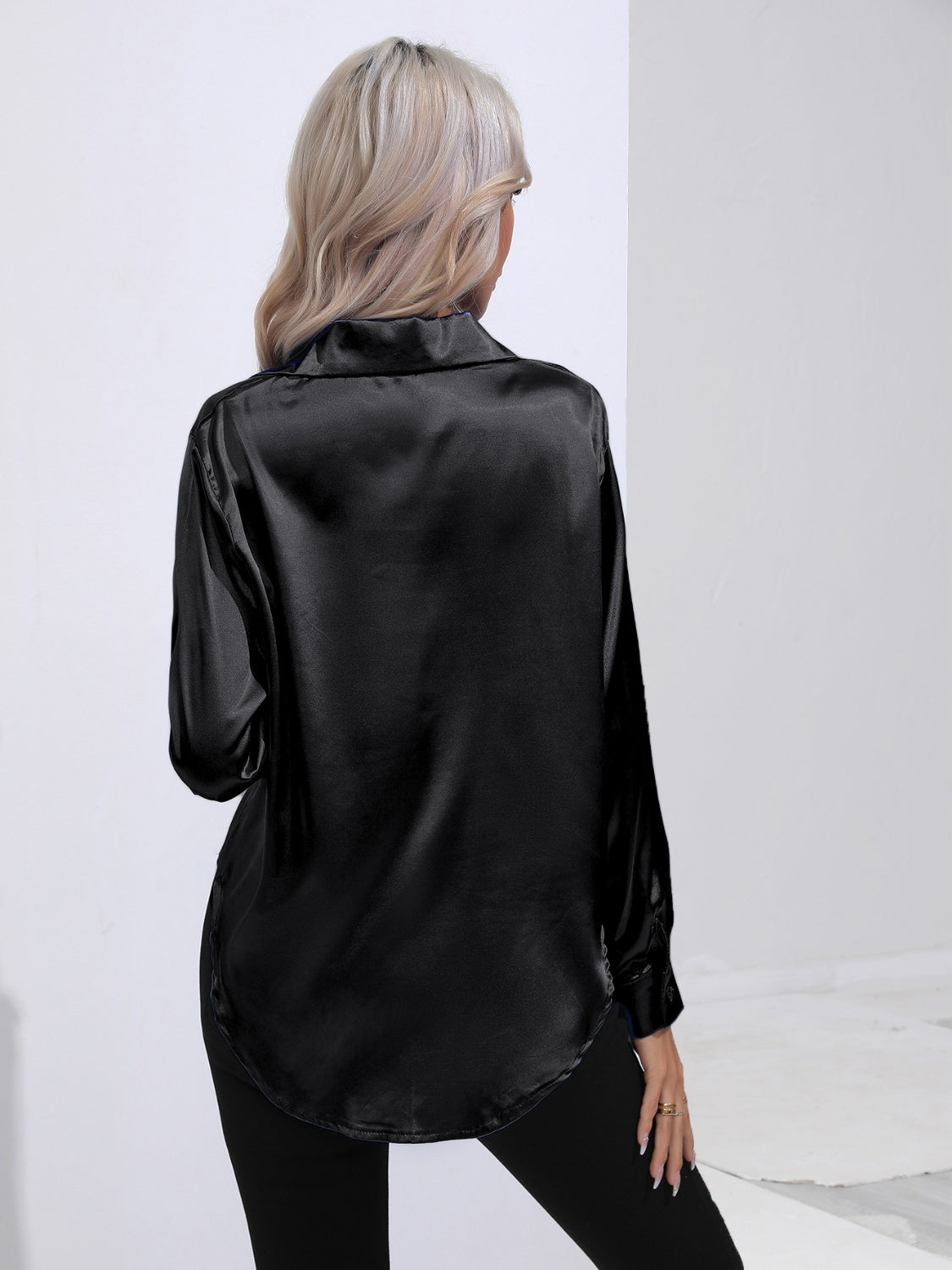 Black satin tie-front blouse with long sleeves and a curved hem.